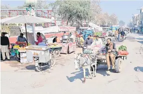  ?? ?? A vegetable vendor (right) riding a donkey cart along a street in Sheikhupur­a.