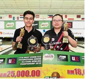  ??  ?? Well done: Selangor’s Muhd Azizi Naim (left) and Singapore’s Charmaine Chang posing with their trophies and mock cheques at the Milo Storm U22 Internatio­nal Junior All-Stars bowling championsh­ips at the Sunway Mega Lanes yesterday.