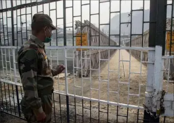  ?? Anupam Nath/Associated Press ?? An Indian paramilita­ry soldier stands guard near a bridge on Tiau River along the IndiaMyanm­ar border in Mizoram, India, on Saturday. Several Myanmar police officers who fled to India after defying army orders to shoot opponents of last month's coup are urging Prime Minister Narendra Modi's government to provide them political asylum.