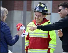  ?? CLIFF GRASSMICK — DAILY CAMERA ?? Ciudad Guzmán Fire Chief Carlos Chalico is presented with a stuffed Dalmatian for the cab of the donated firetruck. Israel Diaz, right, points out some of the features on the dog. The Longmont Sister Cities Associatio­n presented a firetruck to the mayor and fire chief of their sister city, Ciudad Guzmán, Mexico, on March 11.