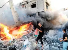  ?? ?? A Palestinia­n man uses a fire extinguish­er to douse a fire following an Israeli strike, in Khan Yunis in the southern Gaza Strip, as fighting between Israel and the Hamas movement continues for the eighth consecutiv­e day.