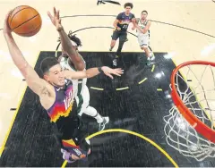  ?? AFP ?? The Suns’ Devin Booker, left, goes up for a slam dunk against the Bucks.