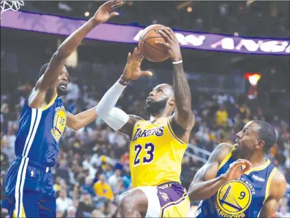  ?? (AP Photo/John Locher) ?? Los Angeles Lakers forward LeBron James (23) shoots between Golden State Warriors forward Kevin Durant, left, and guard Andre Iguodala during the first half of an NBA preseason basketball game Wednesday, October 10, 2018, in Las Vegas.