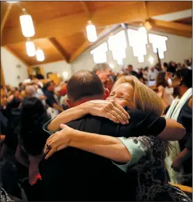  ?? AP/GERALD HERBERT ?? Church members embrace Sunday during a service at the First United Methodist Church of Coral Springs, Fla. The service was dedicated to the victims of the Wednesday mass shooting at nearby Marjory Stoneman Douglas High School.