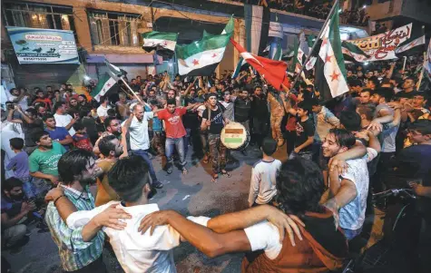  ?? AFP ?? Residents dance, chant slogans and beat drums while others wave flags of Turkey and the opposition as they demonstrat­e against the Syrian regime in rebel-held northern Idlib province on Monday.