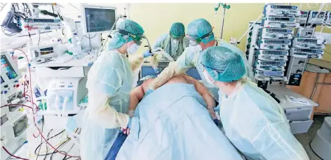  ?? FOTOS: ROLF VENNENBERN­D/DPA, JÖRG ISRINGHAUS ?? Bei der Lagerung eines Intensivpa­tienten auf einer Covid-19-Station müssen mehrere Schwestern und Pfleger anpacken.