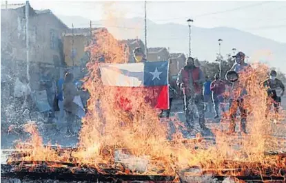  ?? (DPA) ?? Barricada. Un manifestan­te sostenía una bandera chilena frente al fuego ayer en Santiago.