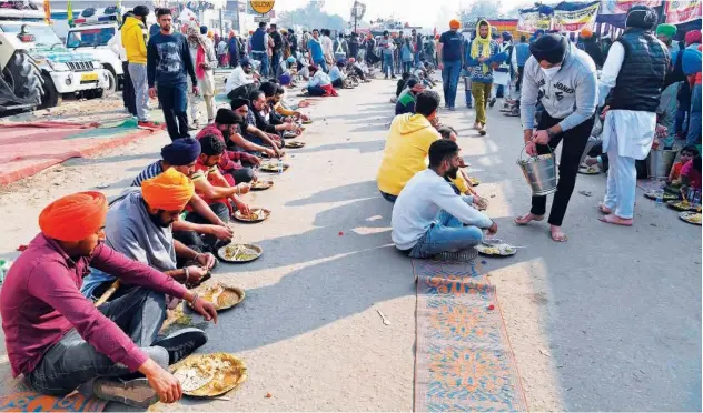  ?? Agence France-presse ?? ↑
Farmers eat on a road in Singhu at the Delhi-haryana border on Thursday.