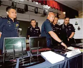  ?? FILE PIC ?? Selangor Commercial Crime Investigat­ion Department head Assistant Commission­er Fazlisyam Abd Majid (third from right) showing equipment used by a scam syndicate in Shah Alam recently.