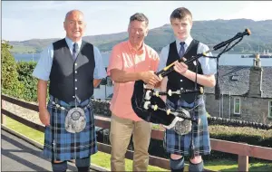  ?? 04_c34bagpipe­s01/04_c34bagpipe­s02 ?? Bob Worrall hands over the pipes to Callum McKillop, alongside Ian McKerral, and Archie McGeachy with his treasured pipes.