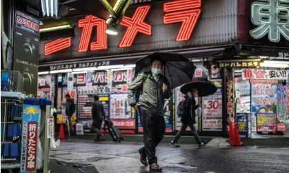  ?? Photograph: Carl Court/ Getty Images ?? A man wearing a face mask in Tokyo, where more than 20,000 new cases have been reported for 13days running.