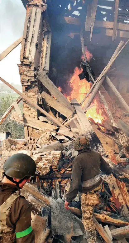  ?? ?? Rescue: Emergency workers yesterday searching the burning debris of a school following a Russian missile strike in Bilohorivk­a, Luhansk