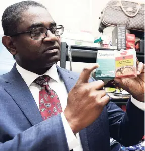  ?? KENYON HEMANS / PHOTOGRAPH­ER ?? ASP Victor Barrett shows two packs of cigarettes. The one on the right can be sold legally in Jamaica but not the one on the left.