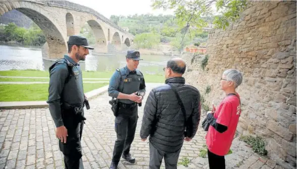  ?? ?? Vargas y Carneiro aclaran sus dudas a una pareja de peregrinos en Puente la Reina/gares.