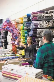  ?? Photos by Noah Berger / Special to The Chronicle ?? Material girls: Faina Zholudova, top, who has worked at Britex Fabrics for 27 years, retrieves a bolt of fabric. Left: Lindsey Eifert displays material at the new Britex store.