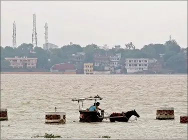  ??  ?? People travel on a horse-drawn carriage through a flooded road on the banks of river Ganga in Allahabad on Sunday, 10 July. REUTERS