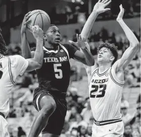  ?? L.G. Patterson / Associated Press ?? A&M’s Hassan Diarra splits Missouri defenders DaJuan Gordon, left, and Trevon Brazile. Diarra later hit two clutch free throws in the final seconds.