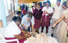  ?? ?? Master potter Phillip Supersad guides Newell High School student, Ashantie Graham, in a pottery-making lesson while other students observe, during the recent Tourism Product Developmen­t Company Limited Youth Expo and Career Fair at the Breds Treasure Beach Sports Park in St Elizabeth.