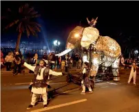  ??  ?? Artists perform during the festival parade, while pulling along a lit-up elephant float at Khalid Lagoon.