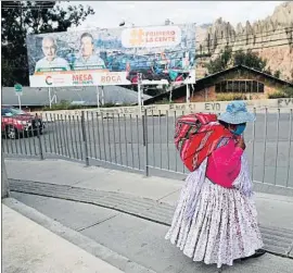  ?? JUAN KARITA / AP ?? Una mujer acarrea un fardo en El Alto , con un cartel electoral al fondo