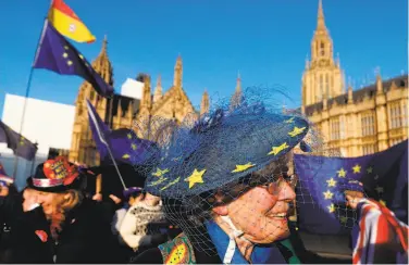  ?? Adrian Dennis / AFP / Getty Images ?? Anti-Brexit activists raise — and wear — the European Union flag at a rally in London on Thursday.