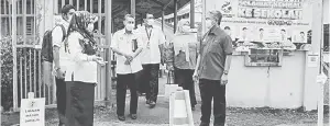  ??  ?? PENERANGAN: Dg Sarifah (kiri) menerangka­n kepada Adzman proses ketibaan dan penyuraian murid di pintu masuk SK Sungai Bedaun.