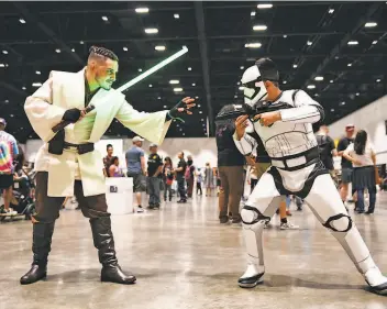  ?? Photos by Cody Glenn / Special to The Chronicle ?? Rigo Luna of Redwood City, dressed as Ben ObiWan Kenobi from “Star Wars,” battles his younger brother David, dressed as a Storm Trooper, during Silicon Valley Comic Con on Saturday, Aug. 17.