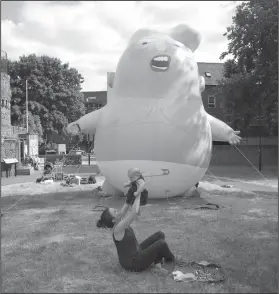  ?? AP Photo/Matt Dunham ?? Parade balloon on display: In this photo taken on Tuesday, July 10, 2018, Ruth Armitage and her nine-month old baby Ivy pose for the media in front of a six-meter high cartoon baby blimp of U.S. President Donald Trump during a practice session in...