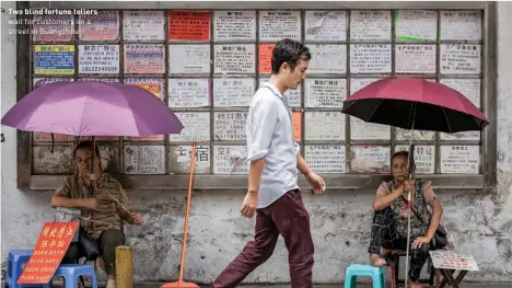  ??  ?? Two blind fortune tellers wait for customers on a street in Guangzhou