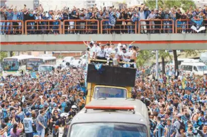  ?? AFP / ITAMAR AGUIAR ?? Campeões da Libertador­es, jogadores do Grêmio desfilam em carro aberto pelas ruas de Porto Alegre