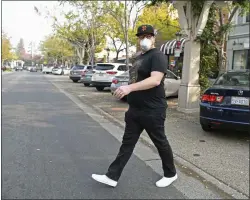  ?? JOSE CARLOS FAJARDO — STAFF PHOTOGRAPH­ER ?? Wearing a mask, Ben Tomassetti, of San Francisco, crosses First Street to pick up food in Livermore on Thursday.