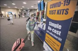  ?? Allen J. Schaben Los Angeles Times ?? HOLLY Goodwin picks up coronaviru­s self-collection kits at John Wayne Airport on Tuesday. The last two years have scarred the country, Thomas Curwen writes.