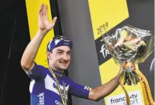  ?? Jeff Pachoud / AFP / Getty Images ?? Stage 4 winner Elia Viviani of Italy, a sprinting specialist, celebrates on the podium with a bouquet of flowers.