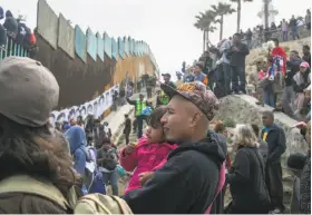  ?? Meghan Dhaliwal / New York Times ?? Refugees from Central America who traveled as a caravan through Mexico gather with supporters at the border wall with the United States in Tijuana.