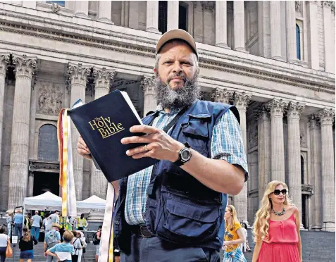  ??  ?? Alan Coote, a bus driver, reads the Gospel aloud from the precincts of St Paul’s Cathedral in London, where staff there have tried to move him on, calling the police to arrest him