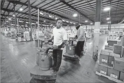  ?? [TOM DODGE/DISPATCH] ?? Josh Gregory, front, and Charles Barlowe travel through the pick area of the shipping dock at Spartan Logistics on “walkie riders.” Spartan has run four distributi­on sites across the state where liquor is stored until it is sold.