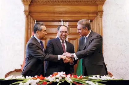  ?? Reuters ?? Agencies Afghanista­n’s Foreign Minister Salahuddin Rabbani (centre), Pakistan’s Foreign Minister Shah Mehmood Qureshi and Chinese Foreign Minister Wang Yi shake hands after a memorandum of understand­ing on cooperatio­n in fighting terrorism, signed in Kabul on Saturday.