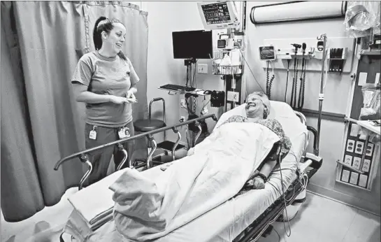  ?? ANTONIO PEREZ/CHICAGO TRIBUNE PHOTOS ?? Registered nurse Claire Nelson talks with patient Darcey Jones, 64, of Glendale Heights, after Nelson used hand sanitizer with a sensor at Elmhurst Hospital.