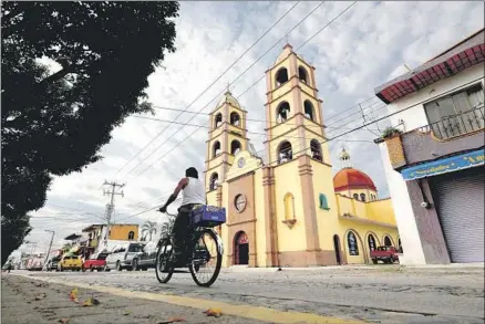  ??  ?? THE CHURCH of San Juan Bautista rises above a street in San Juan, where the economy benefits from nearby Puerto Vallarta.