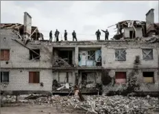  ?? Yasuyoshi Chiba/AFP via Getty Images ?? Workers clean rubble Wednesday atop a building destroyed by shelling a month ago in Cherkaske, eastern Ukraine, during the Russian invasion of the country.