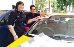  ??  ?? Lee (right) and Sharzede place a VSC car sticker on a taxi’s windscreen during the event yesterday.
