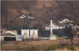  ?? (Tingshu Wang/Reuters) ?? BUILDINGS IN North Korea’s Sinuiju with giant portraits of late North Korean leaders Kim Il Sung and Kim Jong Il are seen from China’s Dandong, Liaoning province, in 2021.