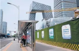  ?? JADE GAO/GETTY-AFP ?? Stringent COVID-19 lockdowns in parts of China have left millions unable to work. Above, a man sits on a bike Thursday in a central business district in Beijing.