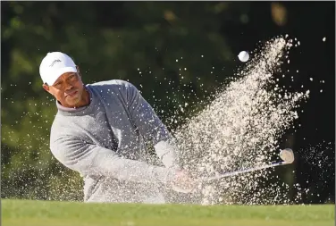  ?? Associated Press ?? Bunker shot: TIGER WOODS HITS FROM THE BUNKER ON THE 18TH HOLE DURING WEATHER DELAYED fiRST ROUND AT THE MASTERS golf tournament at Augusta National Golf Club Friday in Augusta, Ga.