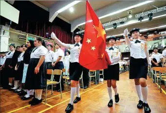  ?? CALVIN NG / CHINA DAILY ?? Students from HKFEW Wong Cho Bau Secondary School in Tung Chung in the New Territorie­s mark the new semester on Sept 2, 2019, by singing the national anthem and taking part in a flag-raising ceremony.