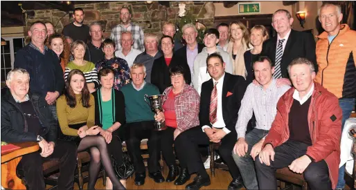  ?? Photo by Michelle Cooper Galvin ?? Breda Foley (seated fifth from left) presenting the John Foley Memorial Cup to winner Dan O’Sullivan, Ardnaknock­een, with his wife, Mary; daughter, Lisa; Chairman Beaufort Beekeepers Ulrich Schraewer; and members at the Beaufort Beekeepers Awards evening in the Beaufort Bar and Restaurant on Thursday.