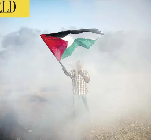  ?? KHALIL HAMRA/THE ASSOCIATED PRESS ?? A Palestinia­n protester waves a national flag during a demonstrat­ion at the Gaza Strip’s border with Israel on Friday.