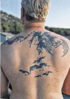  ??  ?? Kirk Silas, a bat biologist, displays his bat-themed tattoos.