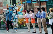  ?? GAO ERQIANG / CHINA DAILY ?? Members of staff welcome visitors to Shanghai Disneyland on May 11. The facility was the first of the Walt Disney theme parks in the world to reopen to the public after closing down on Jan 25 because of the COVID-19 outbreak.