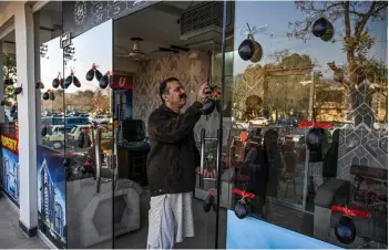  ?? — AFP photo ?? A supporter of Aamir Mughal, member of Pakistan Tehreek-e-Insaf (PTI) party and an independen­t election candidate for the national assembly, pasting his electoral symbol ‘eggplant’ on a glass door, prior to an election campaign meeting in Islamabad.